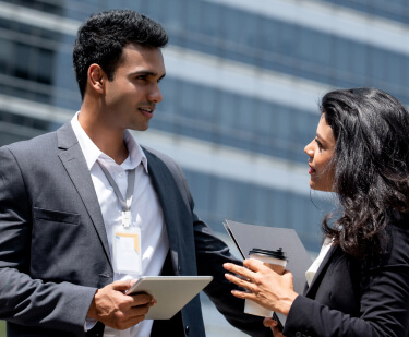 man and woman speaking in front of building